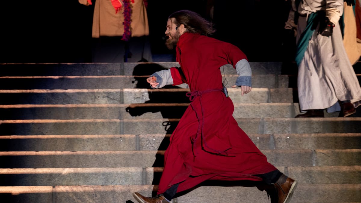 Punaiseen kaapuun pukeutunyt Jeesus  juoksee Senaatontorin portailla Via Crucis-näytelmän harjoituksissa.