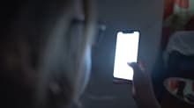 An anonymous youth looks at their phone in the dark