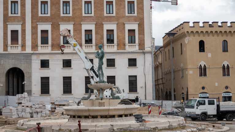 Nosturiauto patsasan takana italialaisella remontoitavalla aukiolla.