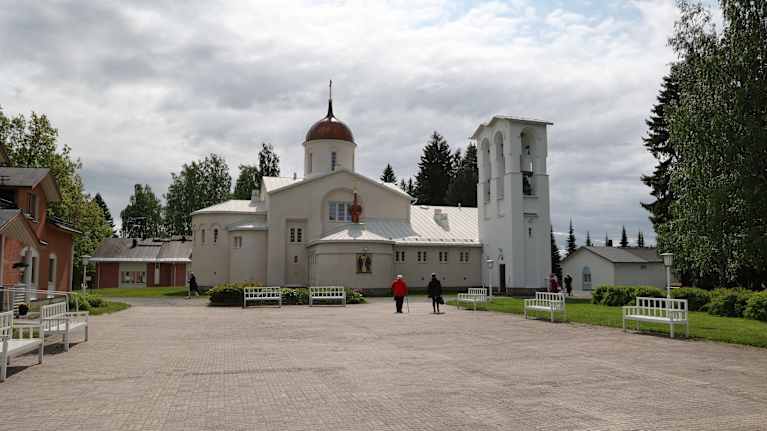 Valamon luostarin kirkon edustalla kaksi matkaajaa.