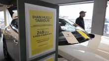 Keltainen tarjouskyltti mainostaa autoleasing tarjousta valkoisen auton kyljessä.