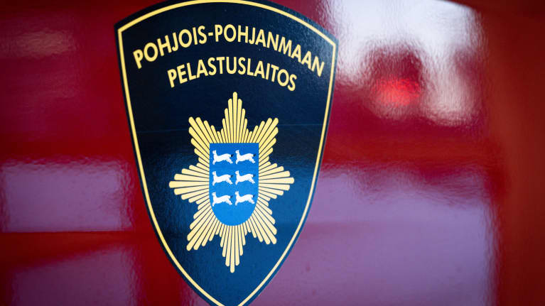 Pohjois-Pohjanmaan pelastuslaitoksen logo hihassa ja palo-autojen kyljessä.