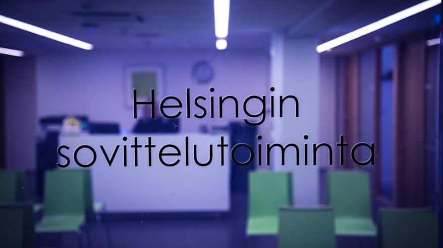 Näkymä Helsingin sovittelutoiminnan toimiston aulaan lasioven takaa.