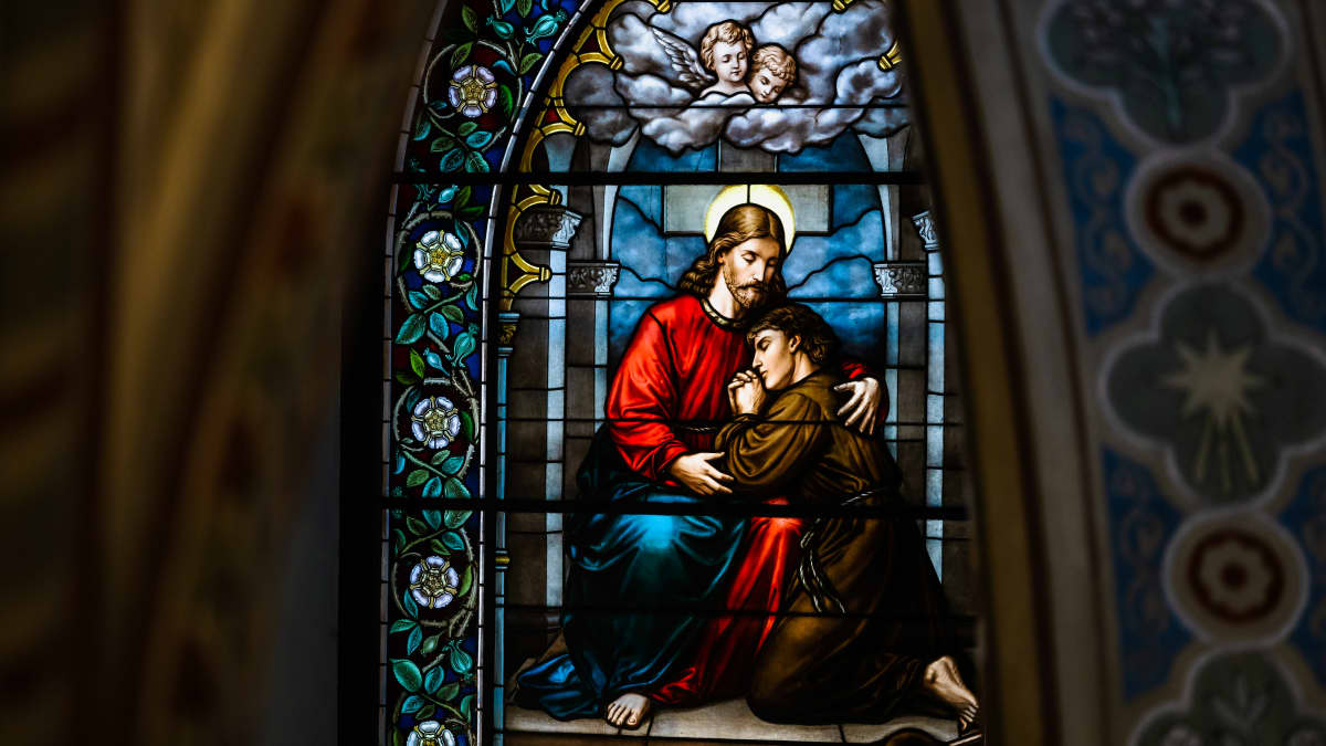 Kirkon alttarin lasimaalaus, jossa Jeesus lohduttaa rukoilevaa ihmistä.