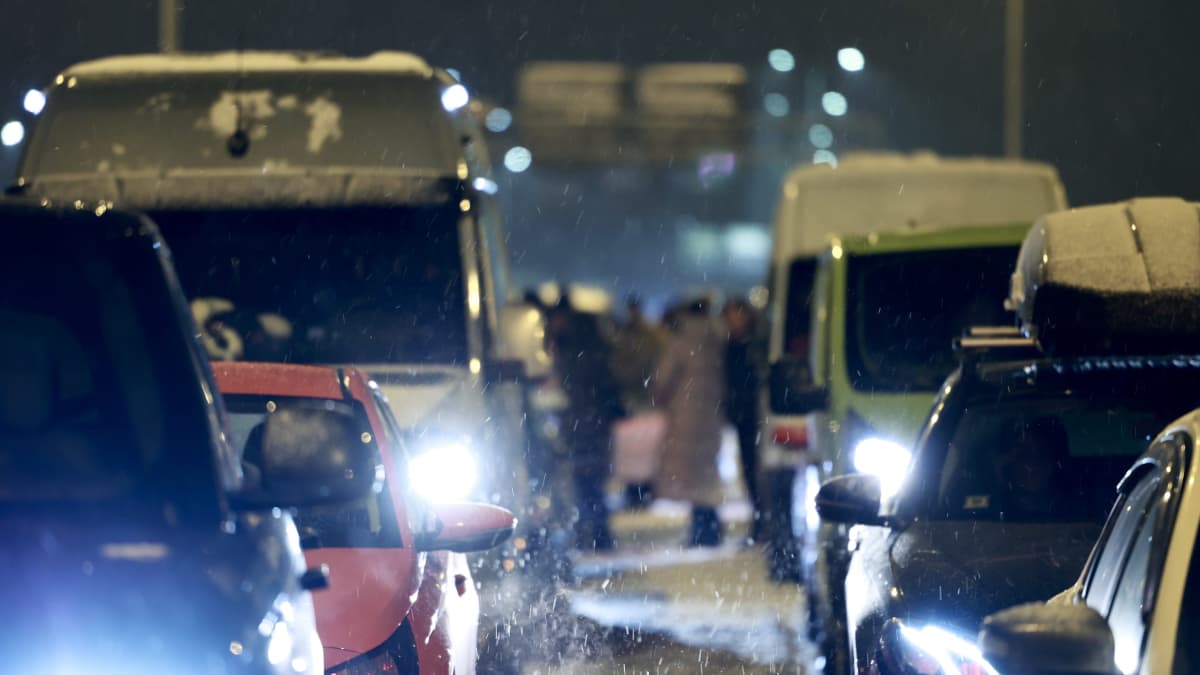 Kuvassa näkyy kun Vaalimaan raja-asemalla ihmiset ovat lähteneet ulos autoistaan, sillä liikenne on pysähtynyt. Kuva on otettu myöhään illalla 14.12.2023
