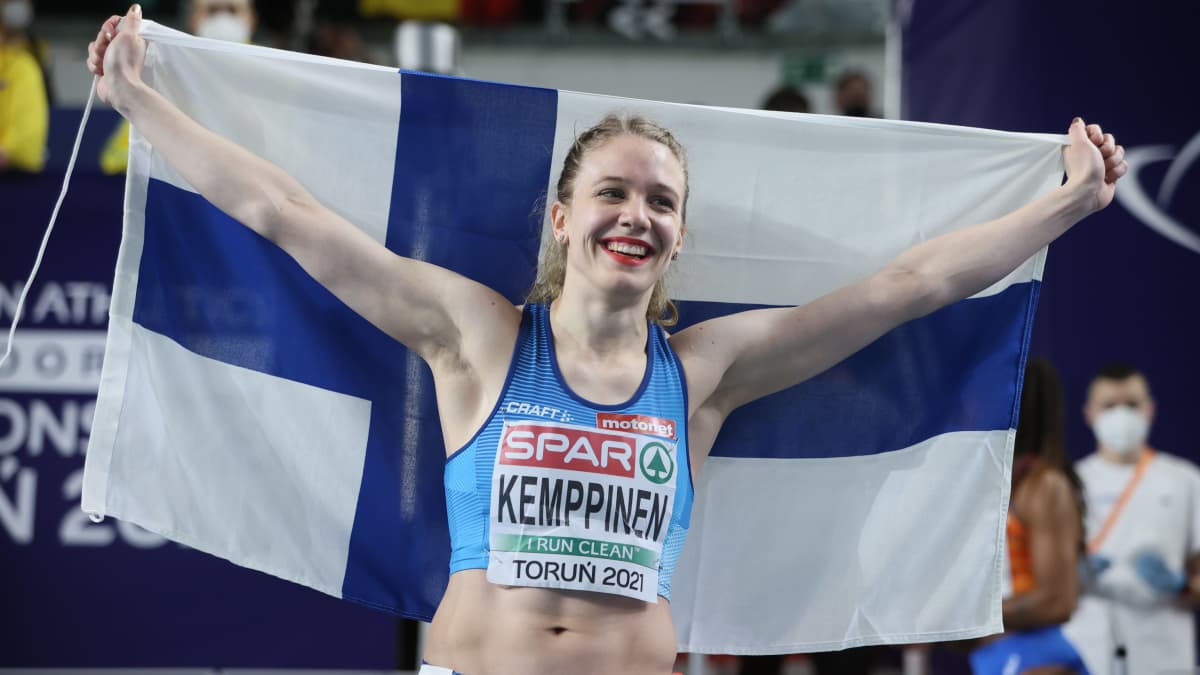 Lotta Kemppinen poseeraa Suomen lipun kanssa.