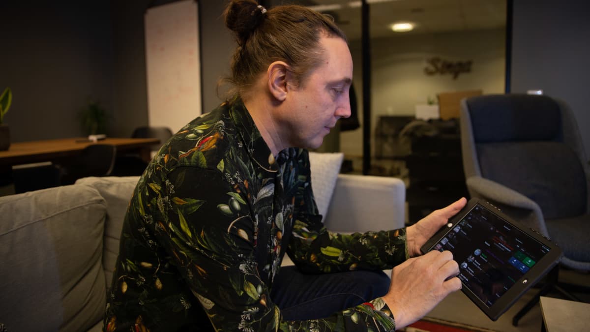 Singa yhtiön Luca Gargano istuu toimistossa sohvalla ja pitää kädessään  tietokonetablettia selaten sillä Singa karaokeohjelman luetteloa musiikkikappaleista.