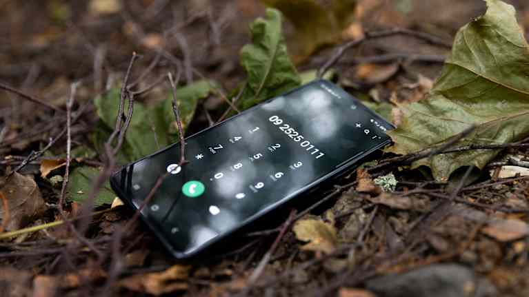 There is a phone on the ground showing the MIELI ry Crisis Hotline number: 09 2525 0111.