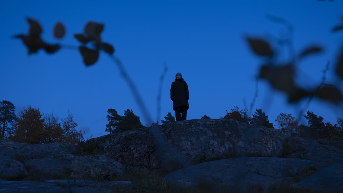 Ihmishahmo seisoo kalliolla.