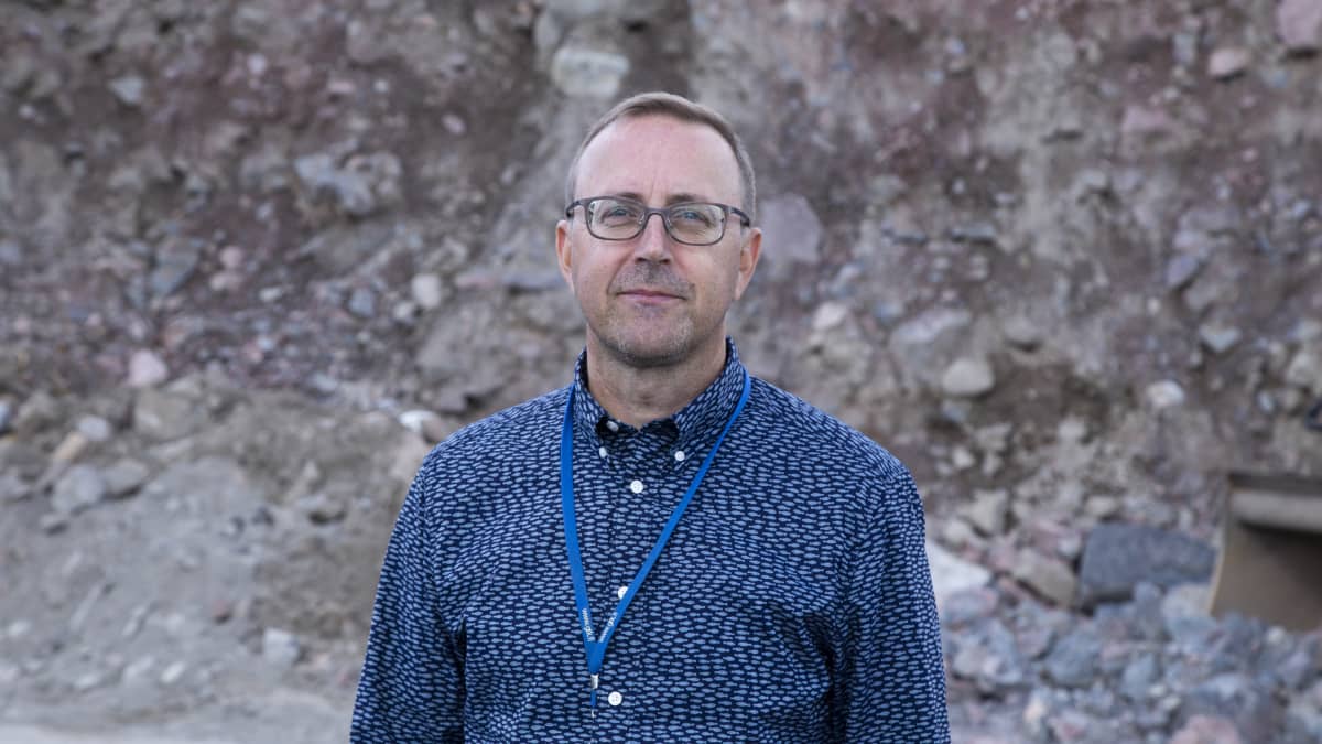 Geologi Jyrki Hämäläinen rakennustyömaalla.Taustalla kivitörmä.