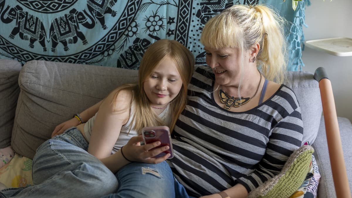 Tytär Vilma äitinsä Kiran kainalossa kodin sohvalla.