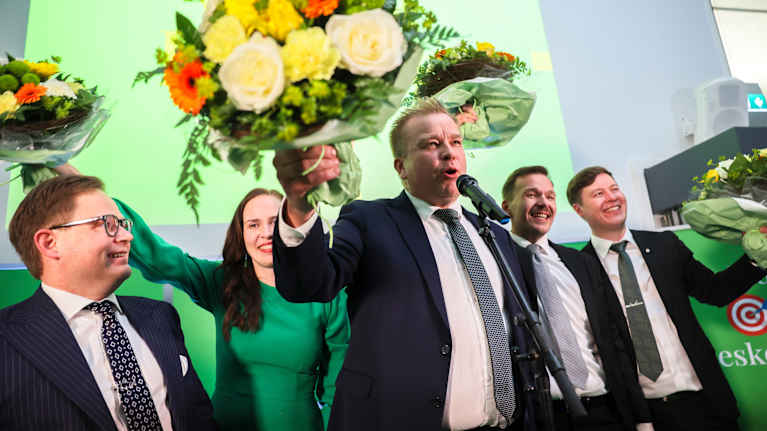 Antti Kaikkonen ja muut keskustan edustajat hurraavat kukkakimppu kädessään.