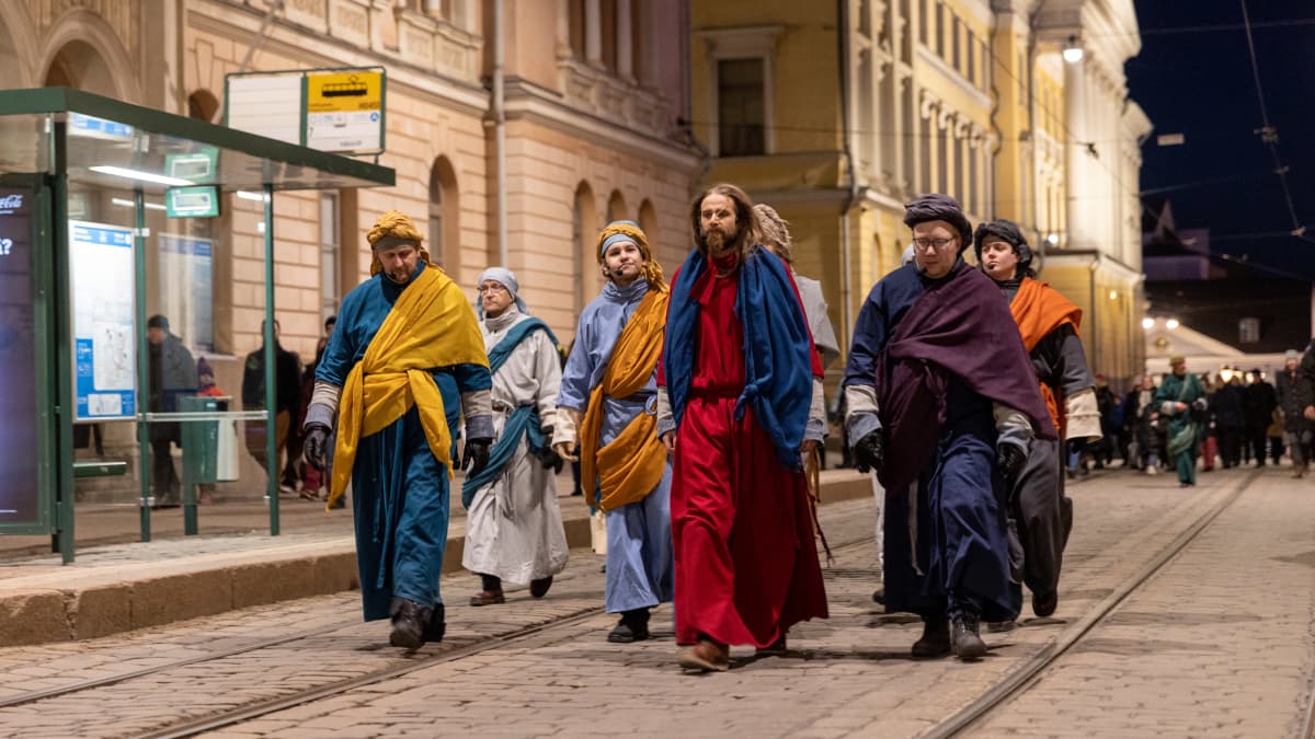 Jeesus ja opetuslapsia kävelee Snellmaninkatua pitkin. Taustalla muita näytelmän esiintyjiä ja yleisöä.