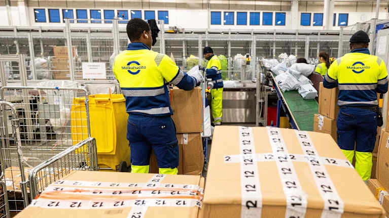 Employees process packages at the Matkahuolto sorting center.