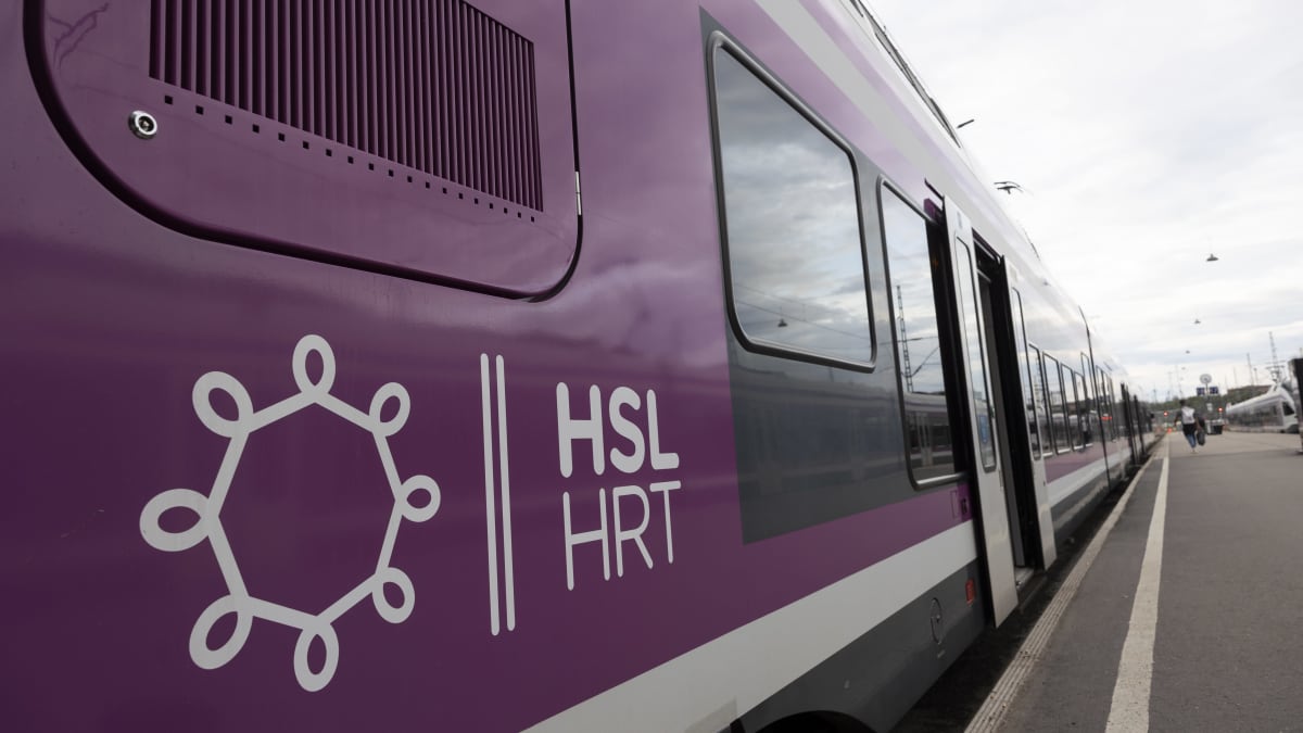 Valko-liila lähijuna pysähtyneenä laiturille. Kyljessä HSL/HRT logo.