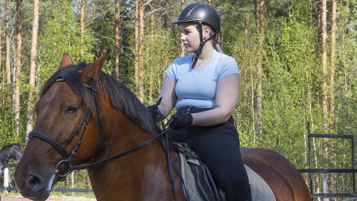 Hilda Merivirta istuu hevosen selässä ratsastuskypärä päässä.