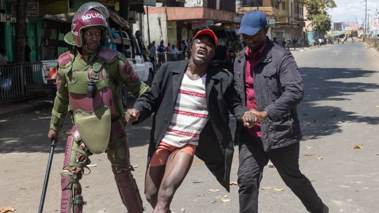 Kenialaiset poliisit taluttavat pidätettyä mielenosoittajaa Nairobin kadulla. 