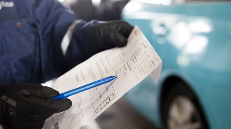 Käsissä paperi ja kuulakärkikynä, joka osoittaa jotain paperilla.