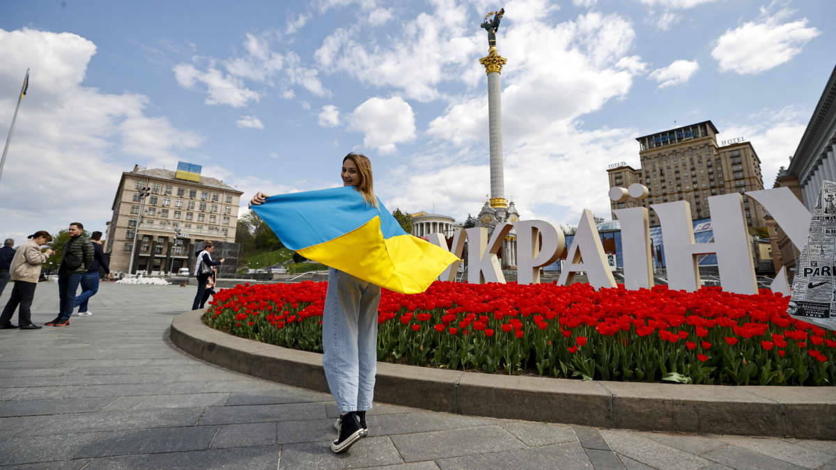 Ihmisiä Itsenäisyyden aukiolla Kiovassa 1. toukokuuta. Etualalla nuori nainen Ukrainan lippu hartioillaan. 