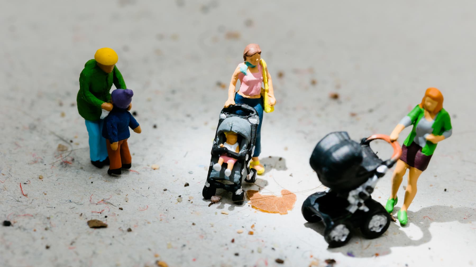 Lapsia ja äitejä esittäviä miniatyyrihahmoja lian ja pölyn keskellä.