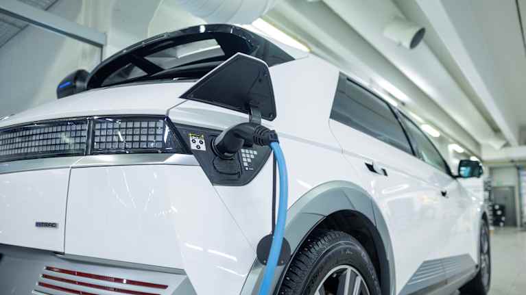A white electric car is charging at a car dealership.
