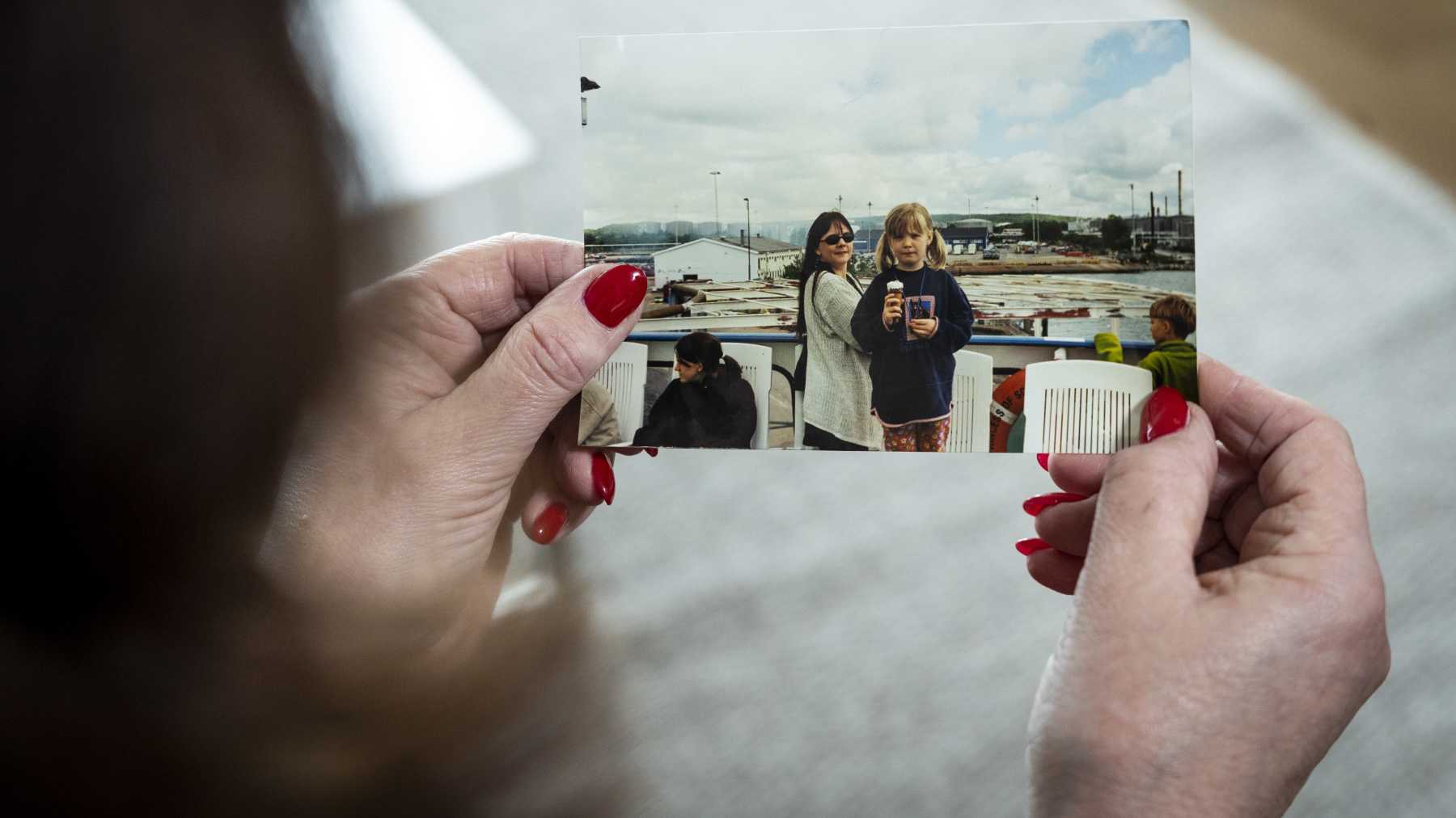 Kaarina Mönkkönen katsoo valokuvaa käsissään, jossa hän ja hänen tyttärensä.