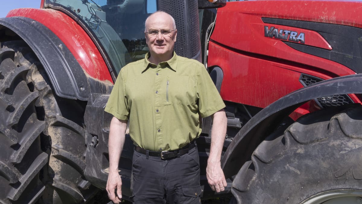 Hämeen ammattikorkeakoulun lehtori Timo Teinilä seisoo suuren punaisen Valtra-traktorin edessä.