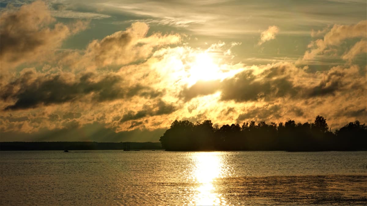 Vaihtelevaa pilvisyyttä. Aurinko paistaa pilven takaa järven ylle. 