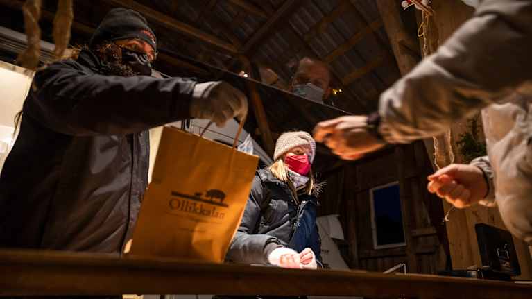Ollikkalan tilan työntekijä ojentaa kassia asiakkaalle
