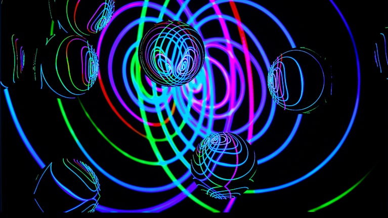 Färgglada linjer och sfärer skapar ett hypnotiskt och abstrakt mönster på en svart bakgrund.