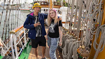 A man and a woman are on the deck of a ship. 