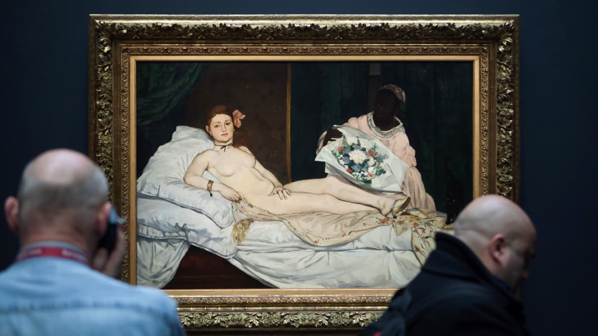 Vierailijoita museossa taulun edessä, jossa renessanssityyliin maalattuna alaston aatelisnainen makaamassa sängyllä.