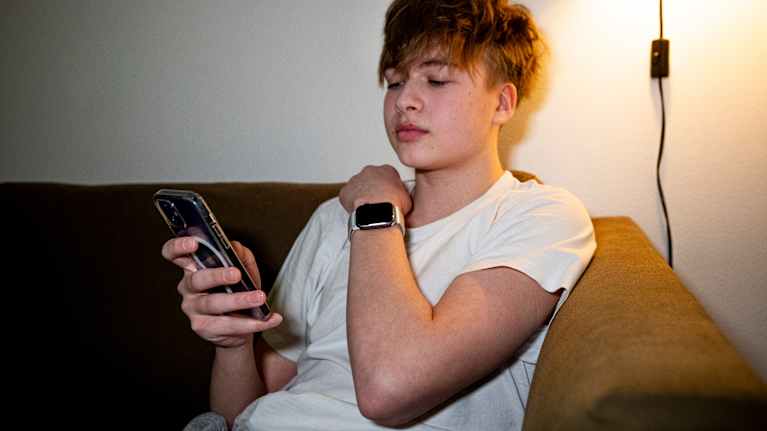 Masi Hartikainen puhelimella kotinsa sohvalla.