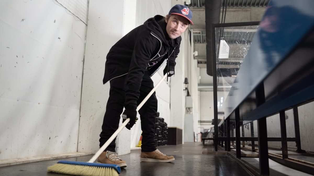 Yhdyskuntapalvelukseen tuomittu Juhani Saunio poseeraa jäähallilla jääkiekkoasennossa harjan kanssa.