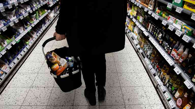Customer carrying shopping cart in grocery store.
