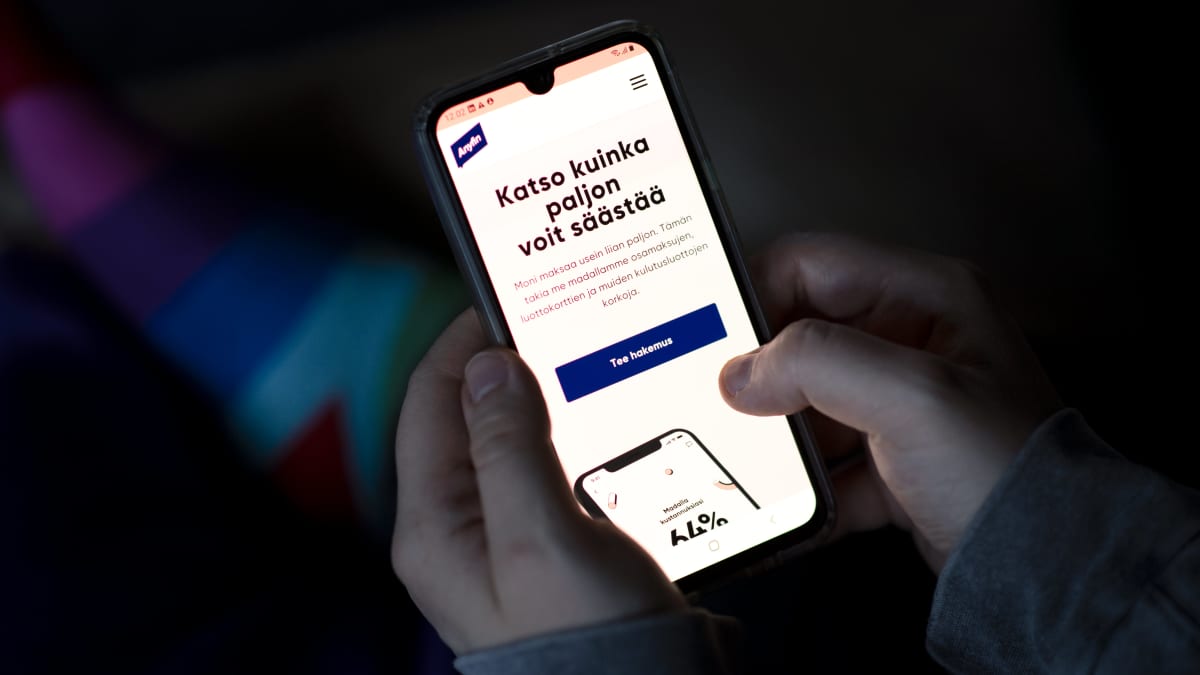 Henkilö katsoo puhelimeltaan järjestelylainaa tarjoavan yrityksen sivustoa.