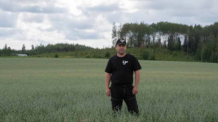 Christian Jensen vid en åker i Paipis, skog i bakgrunden. 