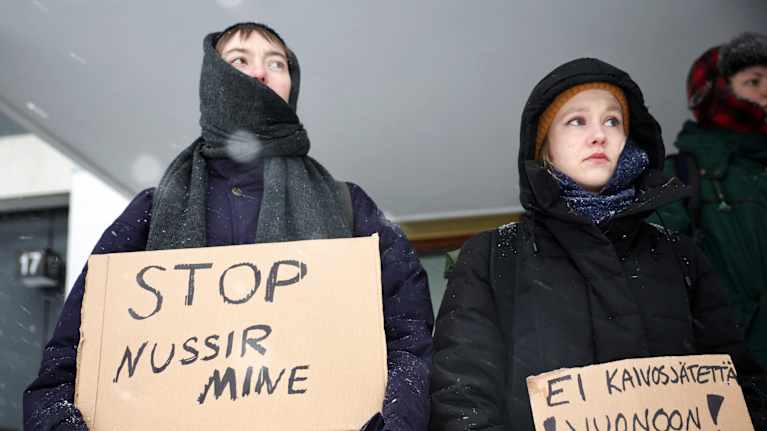 Mielensoittajat pitelevät kylttejä lumisateessa.