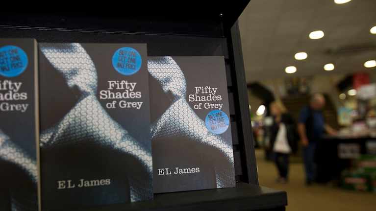 Flera exemplar av romanen Fifty Shades of Grey på en bokhylla.