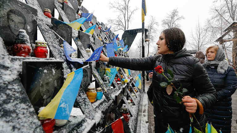 Ukrainalaiset tuovat kukkia ja kynttilöitä kuolleiden muistomerkille Kiovassa. Sodassa on kuollut paljon siviilejä ja sotilaita. Kuva: EPA-EFE