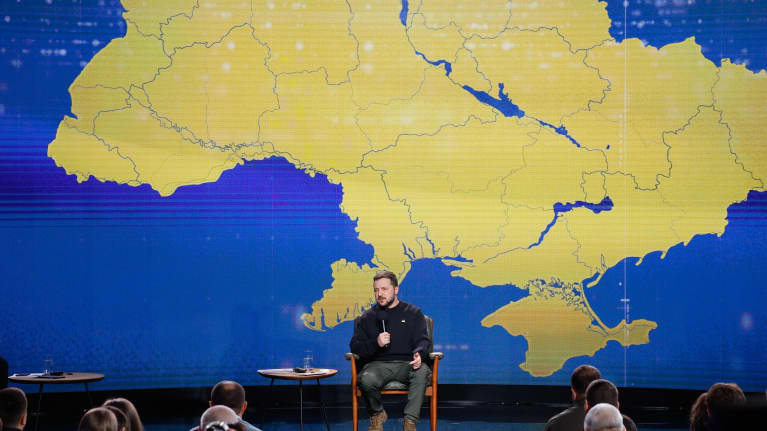 Presidentti Volodymyr Zelenskyi puhuu suuren Ukrainan kartan edessä.