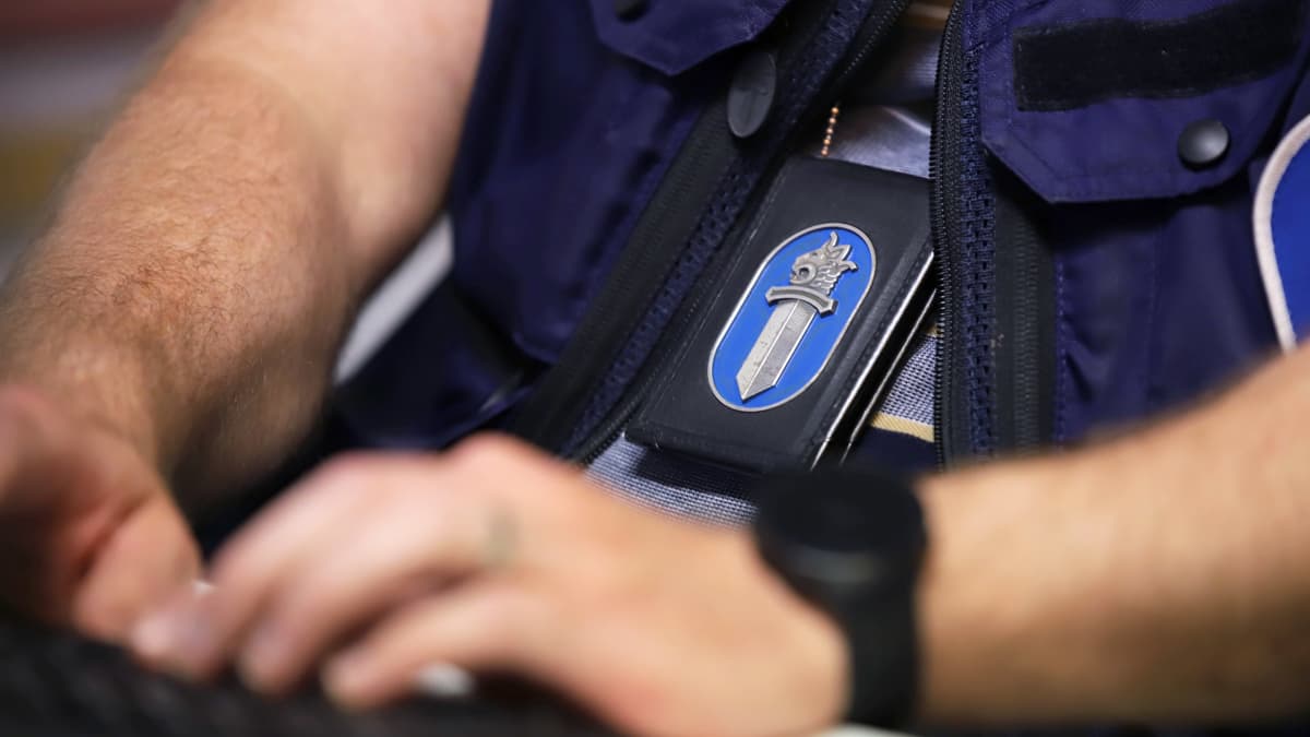 Poliisin virkamerkki tietokoneella työskentelevän poliisin kaulalla.