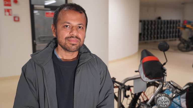 Wolt-kuljettaja Md. Mizanaz Fahman, 2 kk Woltilla, seisoo polkupyöräsuojassa Helsingin rautatieasemalla kameraan katsoen.