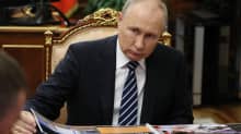Putin selailee pöydällä olevaa lehtiötä