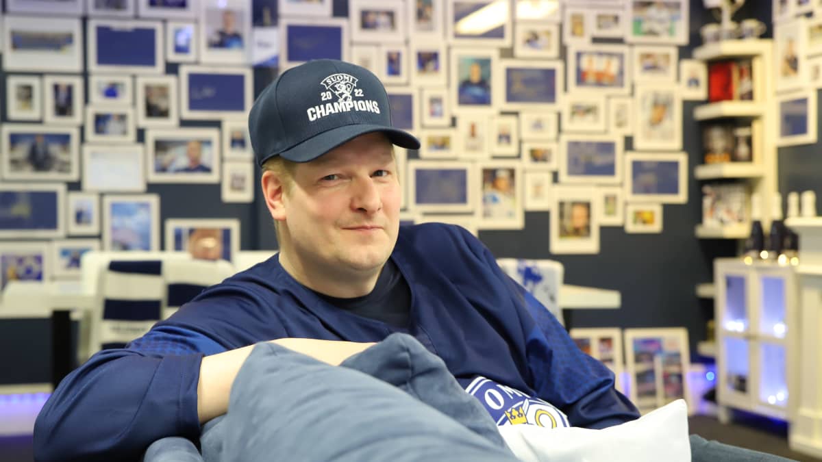 Juha Pitkäniemi katsoo kameraan Leijona-aiheisen autotallin sohvalta.