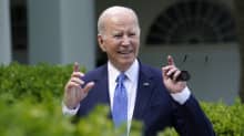 Joe Biden gestikulerar med händerna och ler medan han tittar åt sidan.