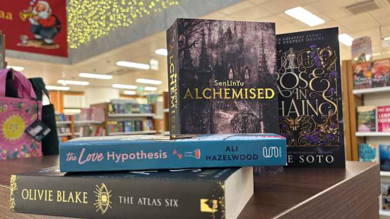 En samling av böcker i fantasy- och romance genrerna staplade på ett bord i en bokhandel.