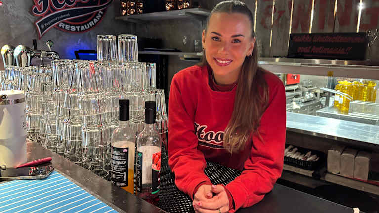 Ravintolapäällikkö Rebecca Vuorio Hook-ravintoloista hymyilee kuvaajalle tiskin takaa.