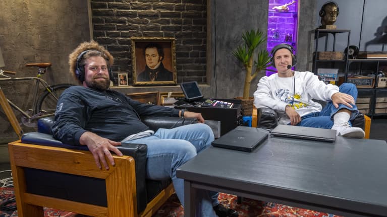 Viki ja Köpi Show:n toimittaja-juontajat Ville “Viki” Eerikkilä ja Juuso “Köpi” Kallio istuvat ohjelman lavasteissa luurit päässä.
