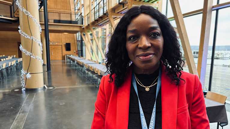 A dark-skinned woman in her red coat.